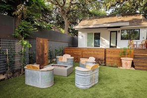 A backyard with a fire pit, outdoor seating, and a house with a window overlooking the yard. - Bangin' Bungalow on South Congress | Heated Pool (Austin)