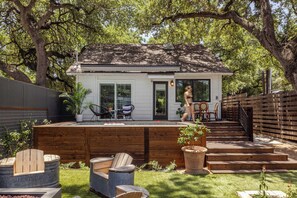 Una casa con terraza, piscina y patio trasero cercado.