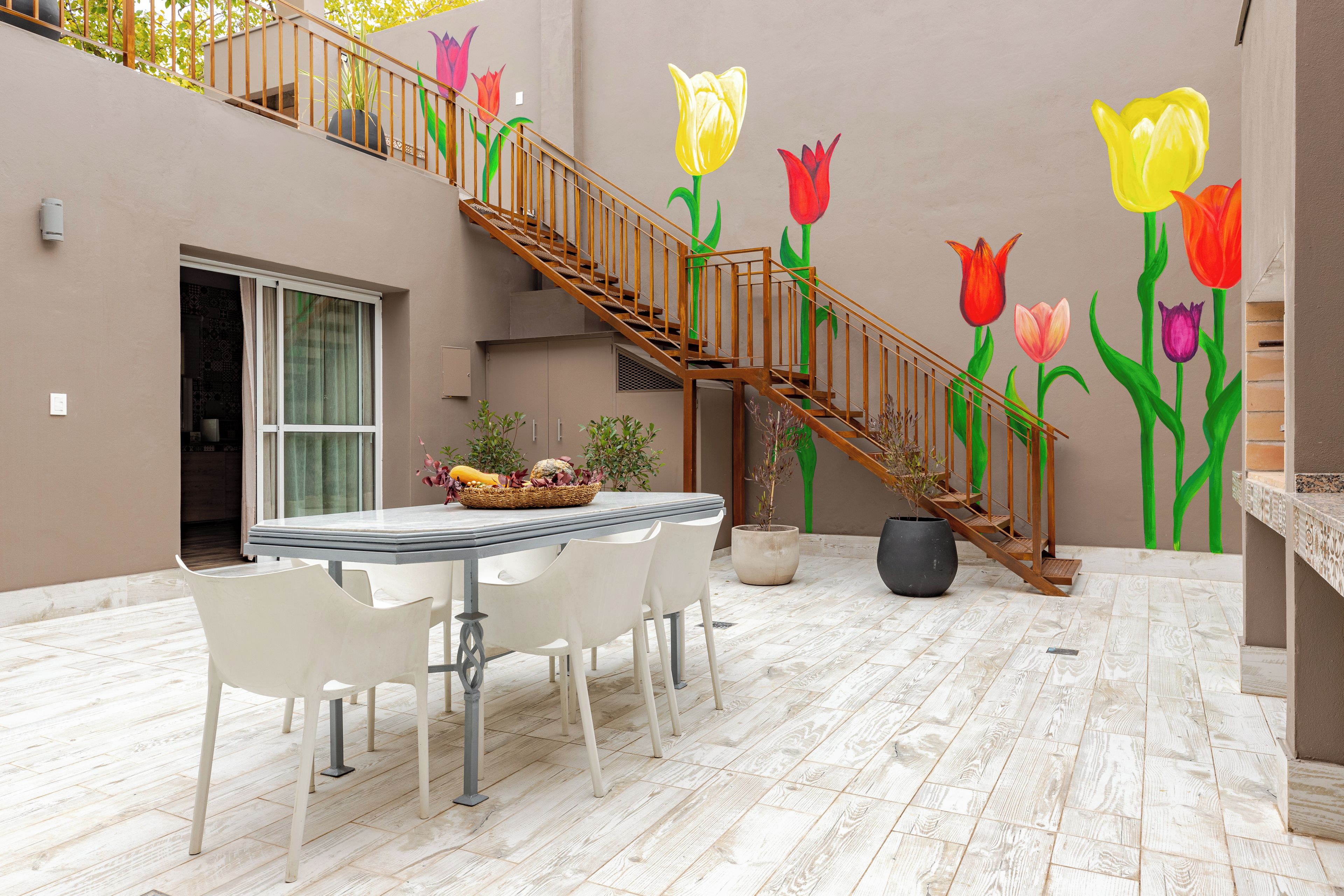 A dining area with a table and chairs, a staircase, and a wall with a floral mural.