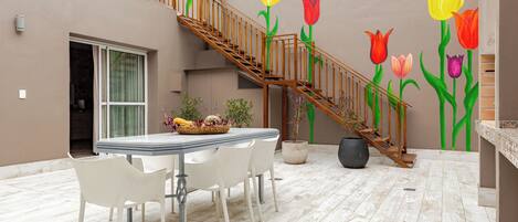 A dining area with a table and chairs, a staircase, and a wall with a floral mural.