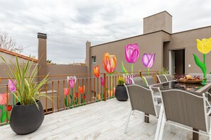 A rooftop terrace with outdoor furniture, a potted plant, and a mural of tulips. - Los Tulipanes House (Mendoza)