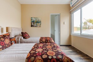 Hotellihuone, jossa on kaksi sänkyä, seinällä taulu ja suuri ikkuna.