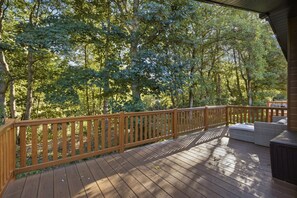 Eine Holzterrasse mit Geländer, umgeben von Bäumen.