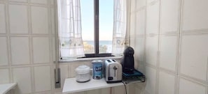 A small kitchenette with a window, a toaster, a kettle, and a water dispenser on a white countertop. - Apartment 'Mar Azul' with sea view, balcony and Wi-Fi (Quarteira)