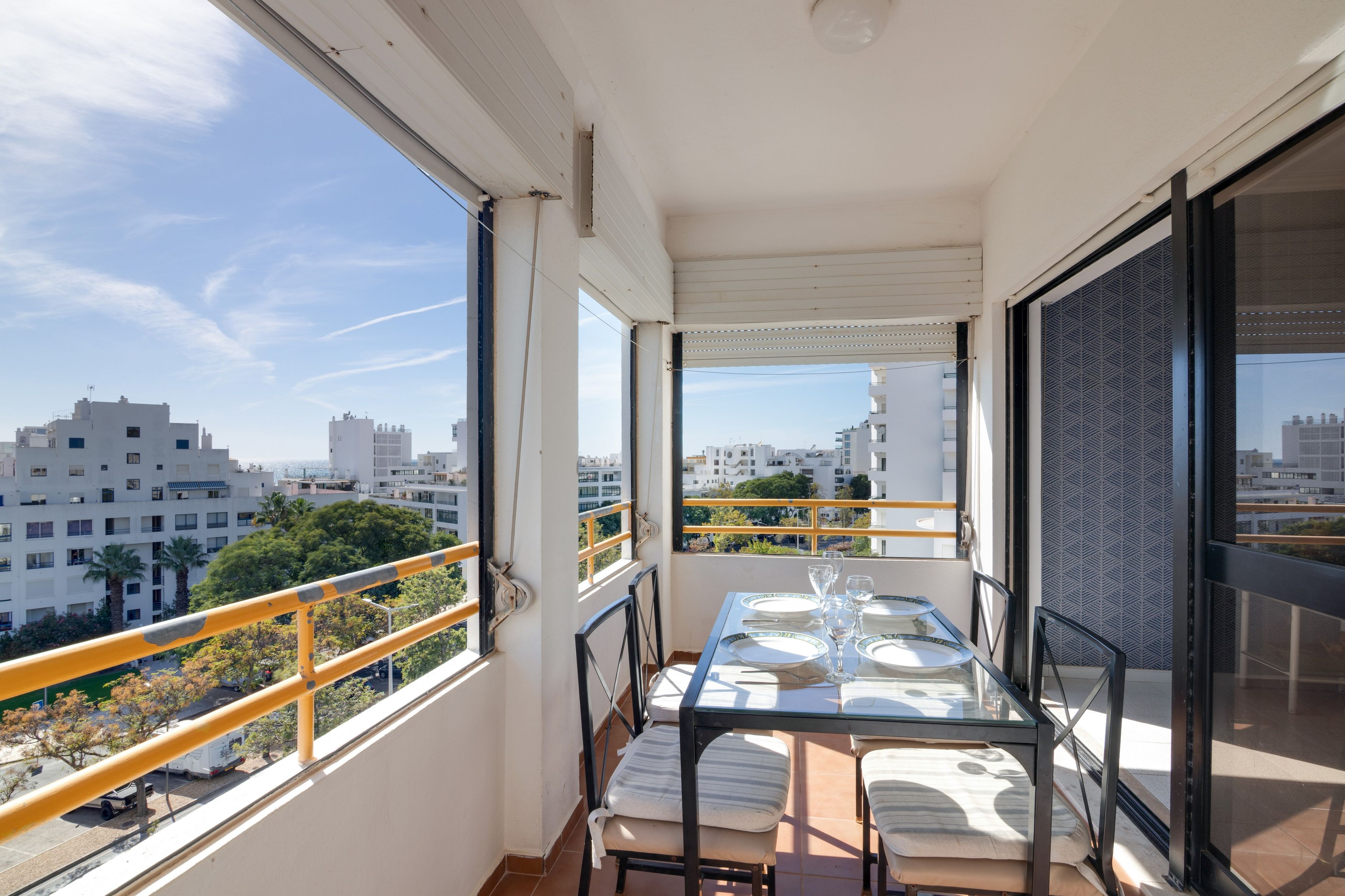 Ein Balkon mit Esstisch, der auf einen Blick über die Stadt mit Gebäuden und Bäumen bietet.