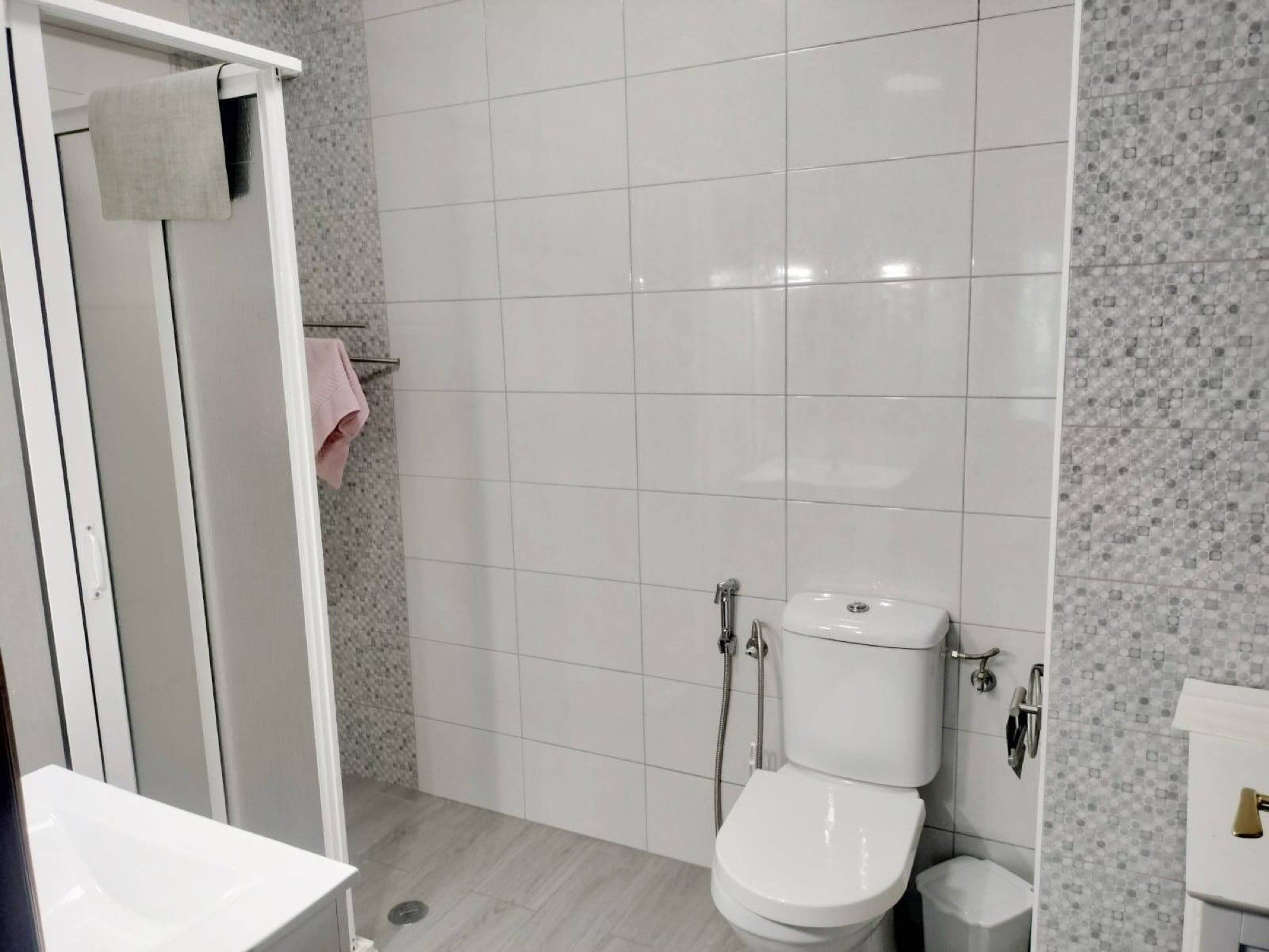 A modern bathroom with a toilet, bidet, and shower area.