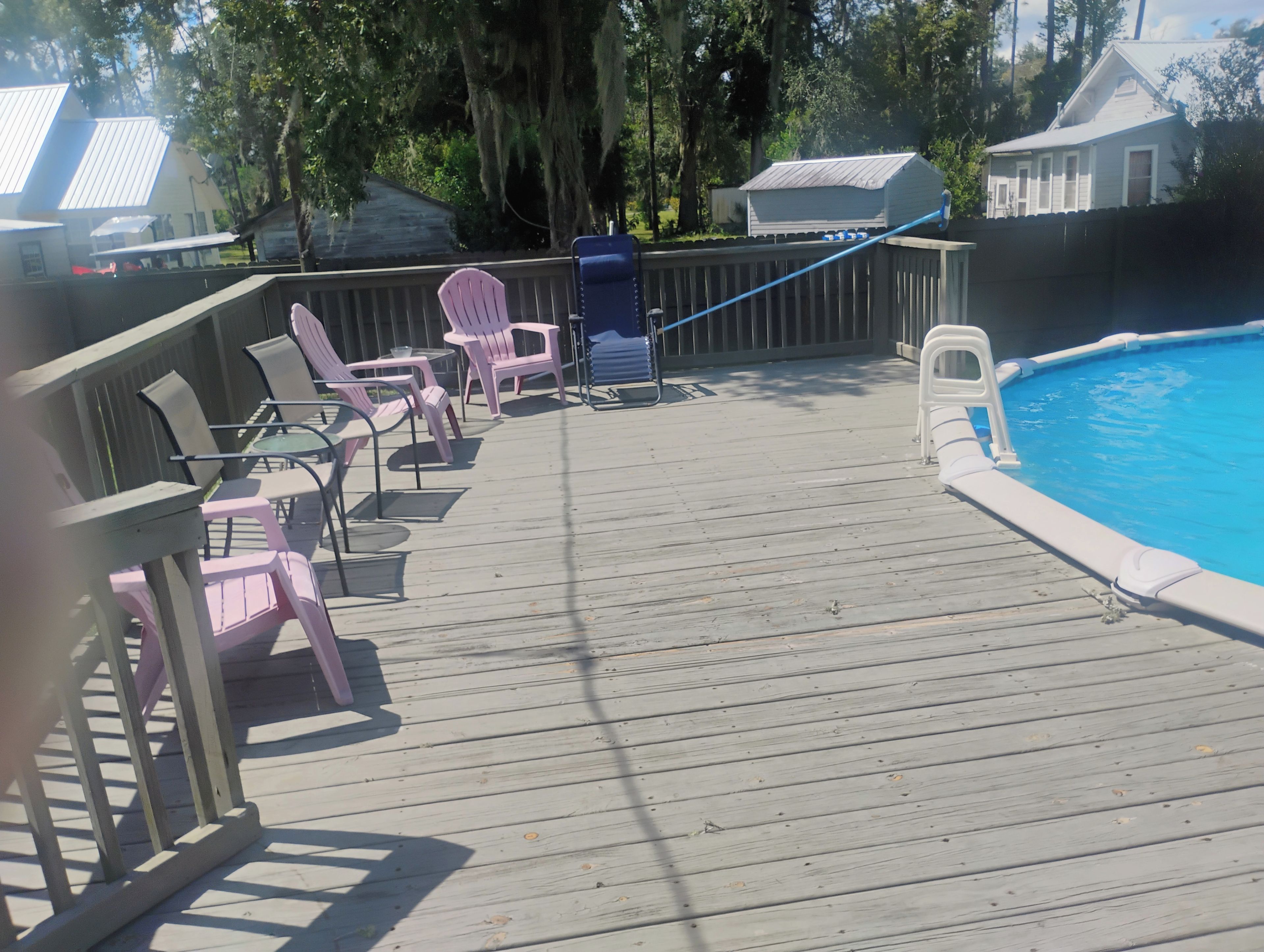 Une terrasse en bois avec des chaises et une piscine.