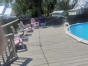 A wooden deck with chairs and a pool.