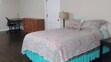 Een slaapkamer met een bed, een dressoir, een bureau en een lamp.