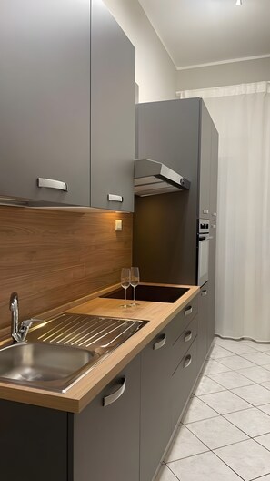 A modern kitchen with a wooden countertop, stainless steel sink, and a built-in oven. - Apartment 'Essential Suite Catania - Luxury' with Balcony, Wi-Fi and Air Conditioning (Catania)