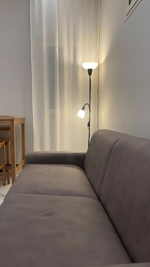 Ein Zimmer mit einer Couch, einem Tisch und einer Stehlampe.