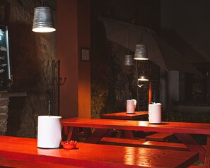 A dimly lit restaurant interior with wooden tables and hanging pendant lights.