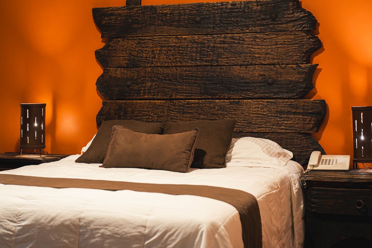 A bed with a wooden headboard, two bedside tables, a telephone, and a lamp.