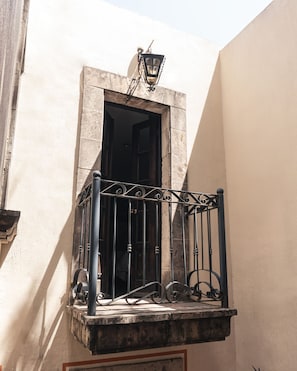 A balcony with a wrought iron railing, a door, and a wall-mounted light fixture.