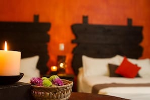 A room with a bed, a lit candle, and a basket of flowers.