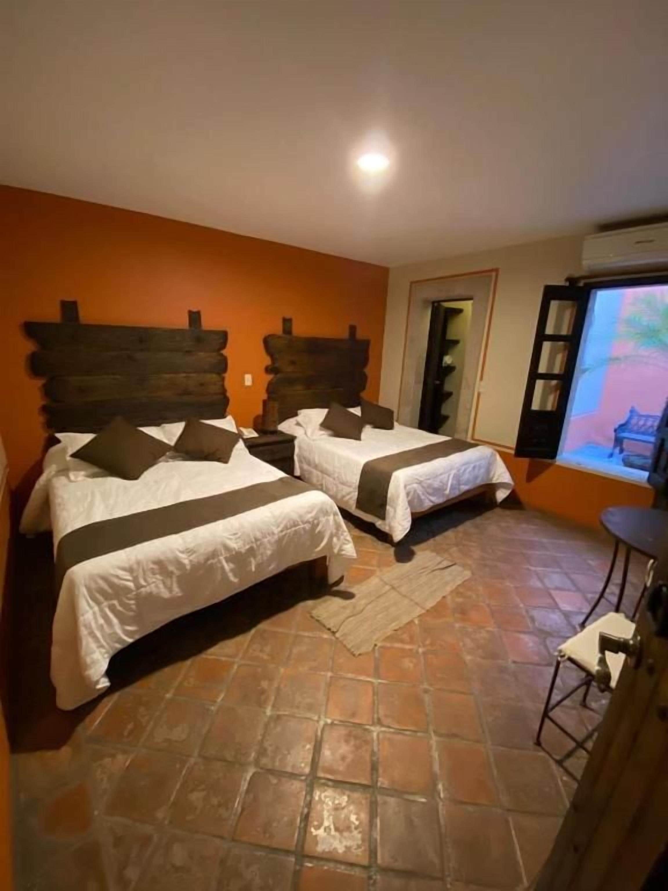 Una habitación con dos camas, una mesita y un televisor.