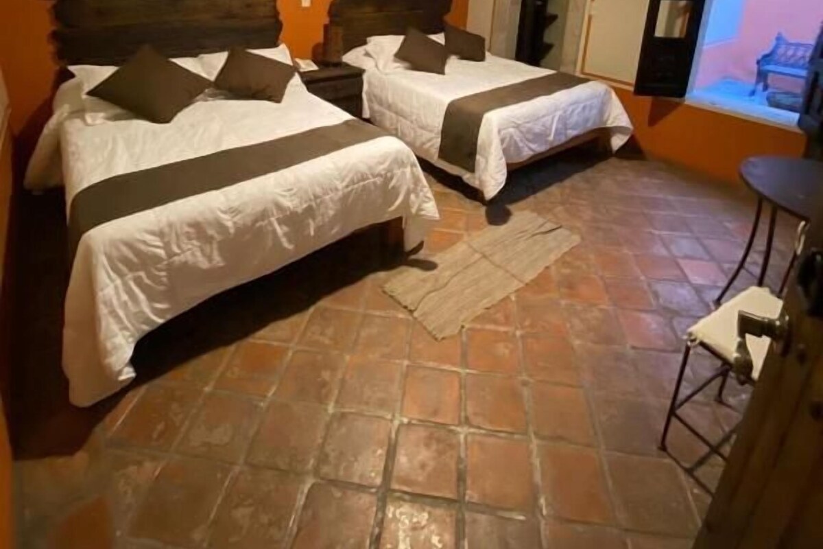 A room with two beds, a small table, and a television.