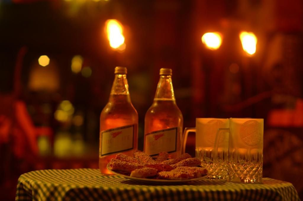A table with two bottles and two glasses, with a plate of food in the foreground.