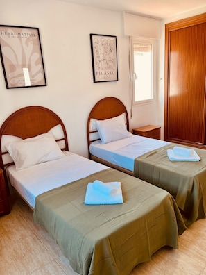 A hotel room with two beds, a wooden wardrobe, and artwork on the walls. - 2 bedroom Apartment sleeps 6, 5 min walk to the beach . (Benalmádena)