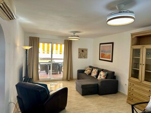 A living room with a sofa, a cabinet, a floor lamp, and a ceiling fan. - 2 bedroom Apartment sleeps 6, 5 min walk to the beach . (Benalmádena)