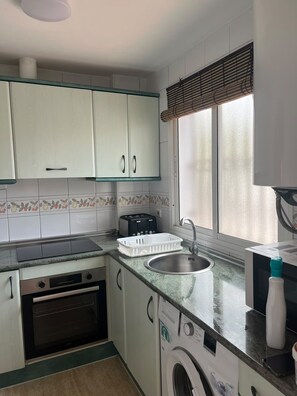 Eine kleine Küche mit Backofen, Waschmaschine und Toaster.