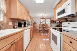A kitchen with wooden cabinets, a white dishwasher, a stove, and a microwave. - Chill at Lakefront Lodge!  Clean, Serene, Comfort (Branson West)