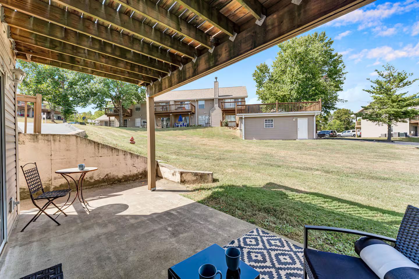 Un patio cubierto con mesa y sillas, un hidrante y vistas a una zona residencial con casas y un garaje.