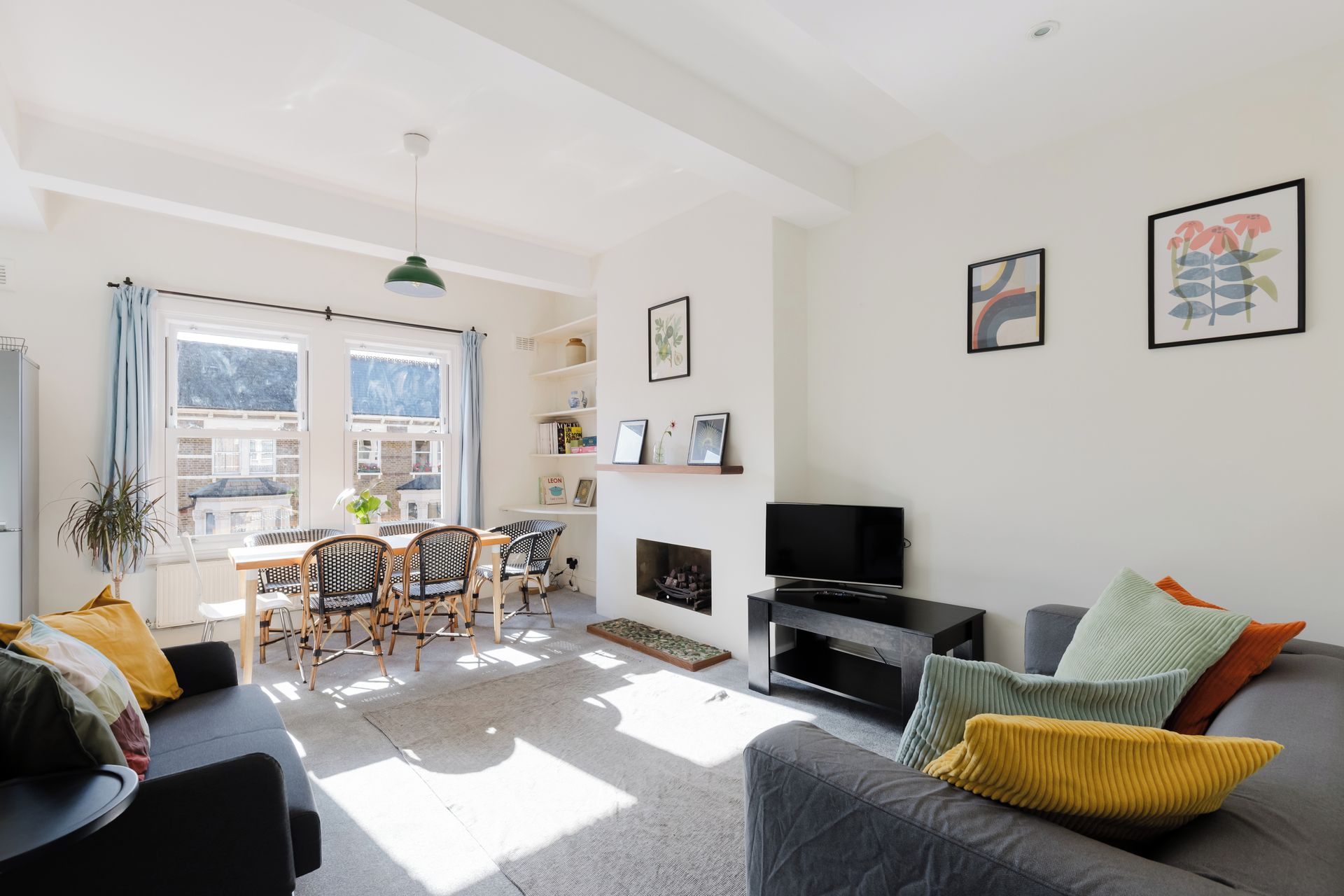 Een moderne woonkamer met een bank, een eethoek met stoelen, een open haard en kunstwerken aan de wanden.