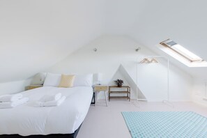Ein Schlafzimmer mit einem Bett, einem Nachttisch, einer Lampe und einem kleinen Holzboden mit einer Pflanze.