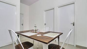 A dining table with four chairs, a bottle, and two placemats.