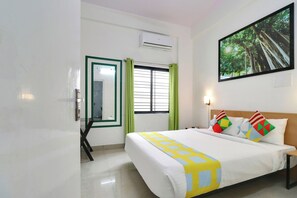 A hotel room with a bed, a window with blinds, a painting on the wall, and an air conditioning unit. - Hotel O Leva Homes Near  (Bangalore)