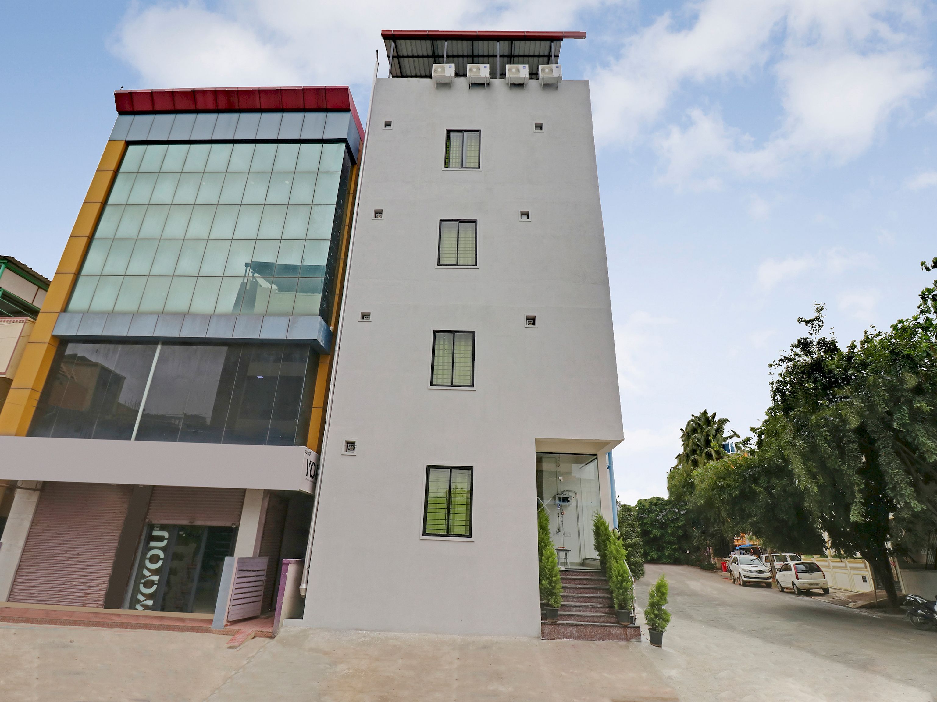 A modern building with a glass facade, a flat roof, and a set of stairs leading to the entrance.
