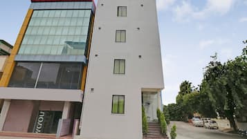 A modern building with a glass facade, a flat roof, and a set of stairs leading to the entrance.