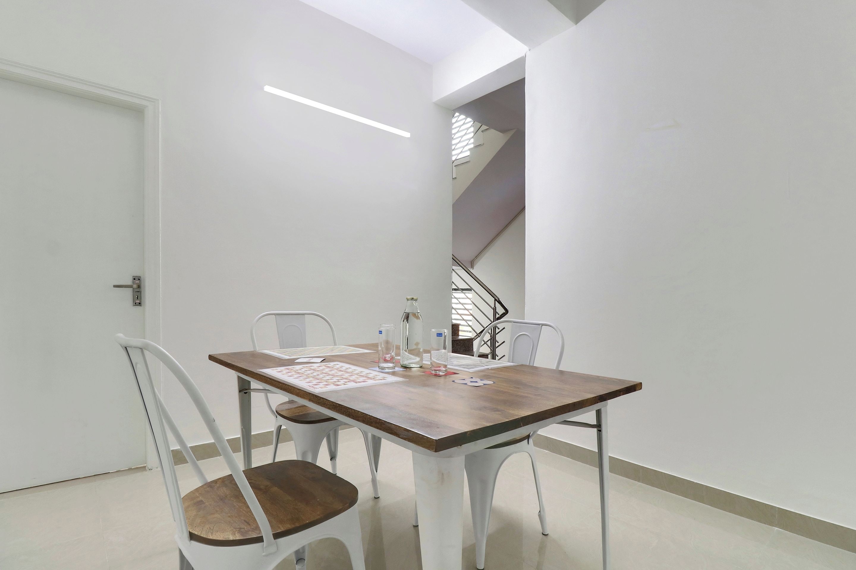 Un comedor con una mesa, sillas, una escalera y una puerta.