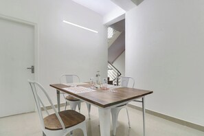 Un comedor con una mesa, sillas, una escalera y una puerta.