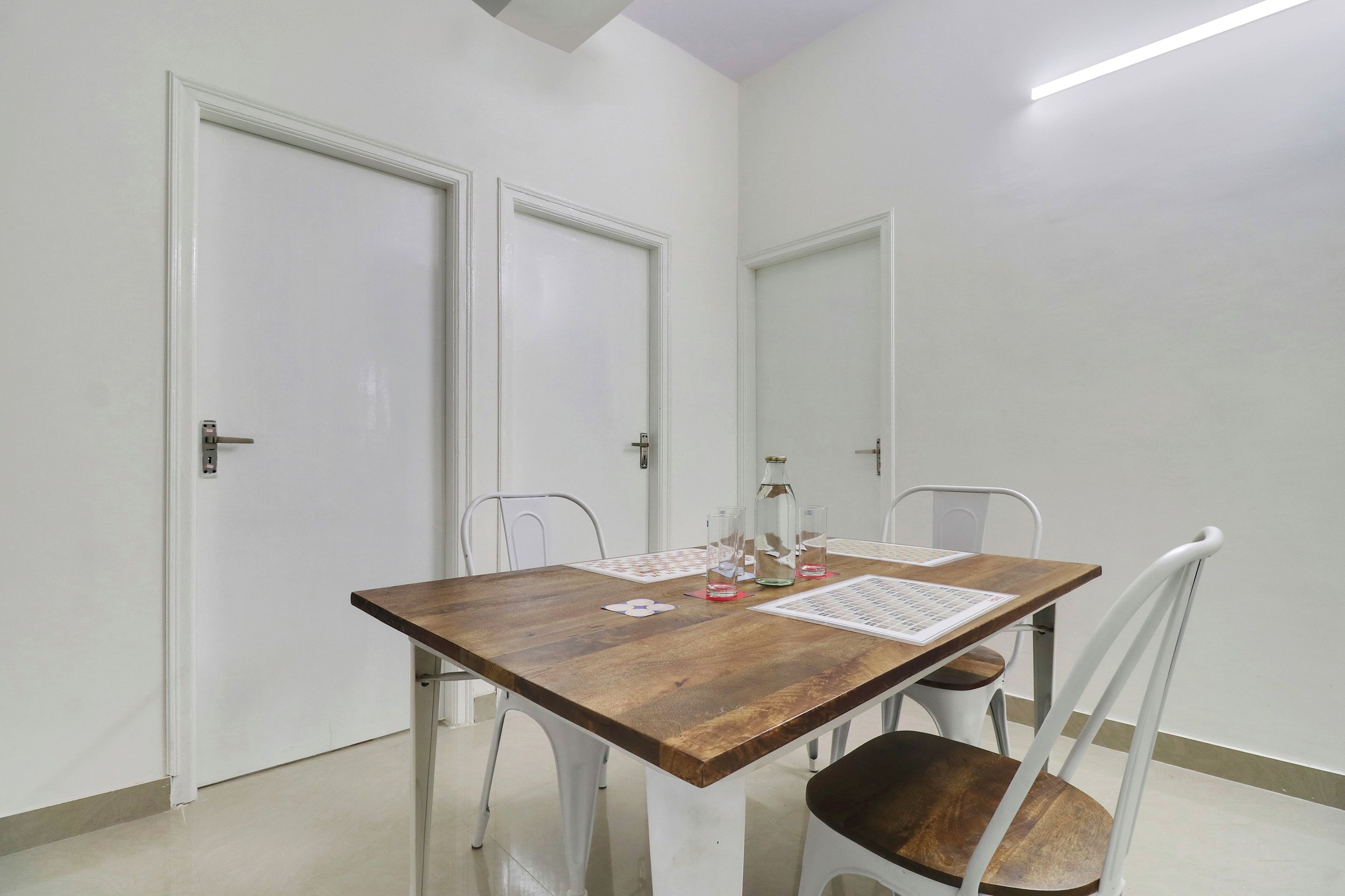 A dining area with a wooden table, white chairs, and a tiled floor.