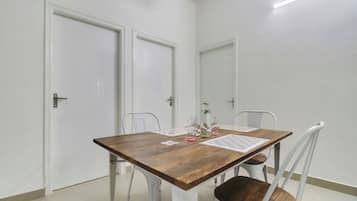 A dining area with a wooden table, white chairs, and a tiled floor.
