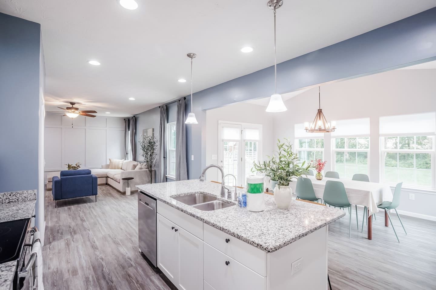 A modern kitchen with a central island, white cabinetry, and a dining area with a table and chairs.