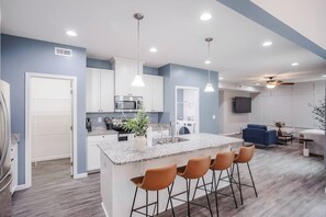 A modern kitchen with granite countertops, white cabinets, and a central island with bar stools. - 4 Bed in Private Community w/Fenced Yard (Lebanon)