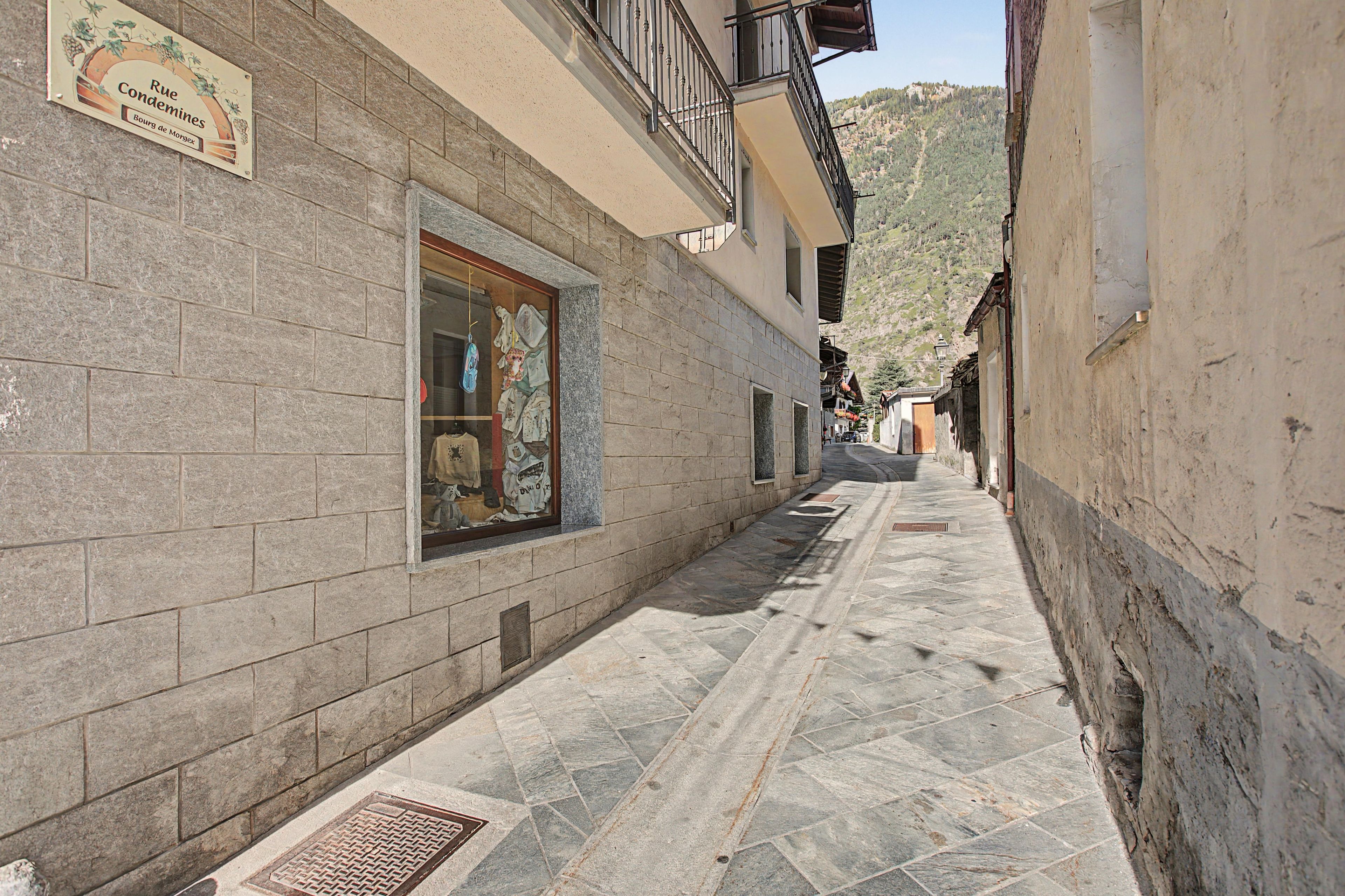 A narrow alleyway with stone walls and a window displaying various items.