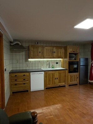A kitchen with wooden cabinets, a dishwasher, a microwave, and a refrigerator. - Apartment 'Maison Condemines' a stone's throw from Courmayeur and La Thuile (Morgex)