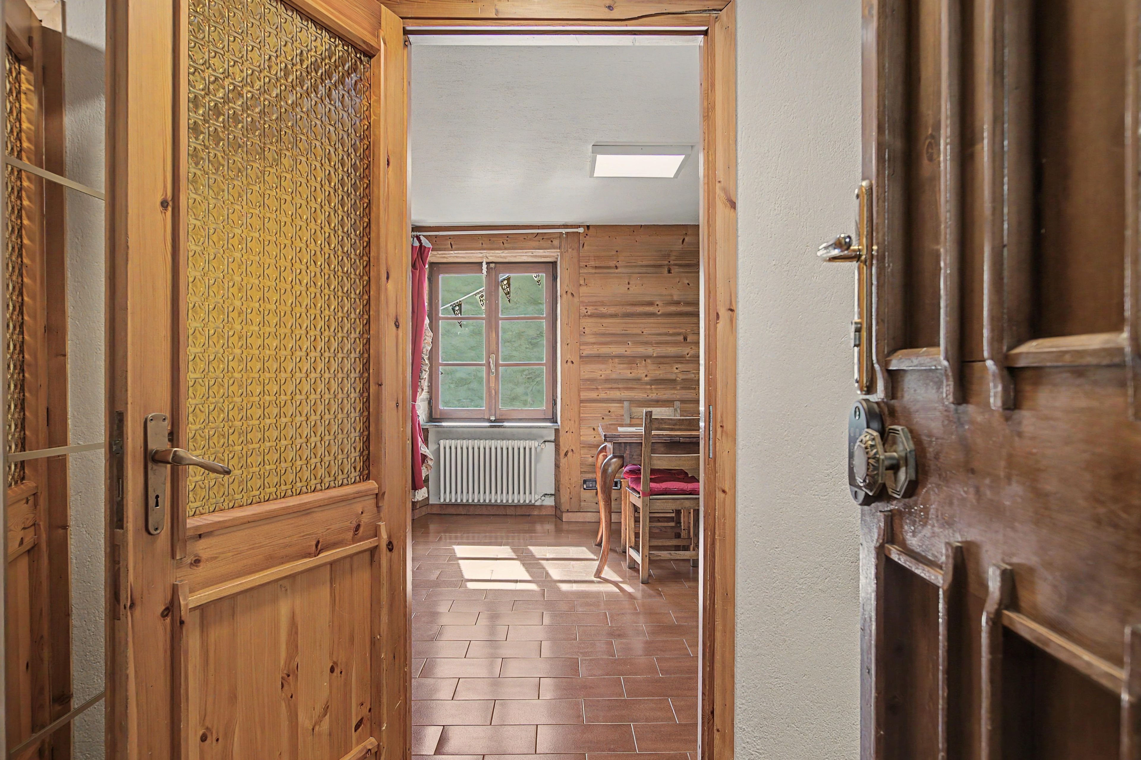 A wooden interior hallway with a radiator, a window, and a door.