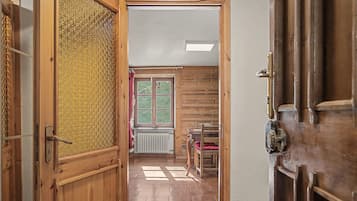 A wooden interior hallway with a radiator, a window, and a door.