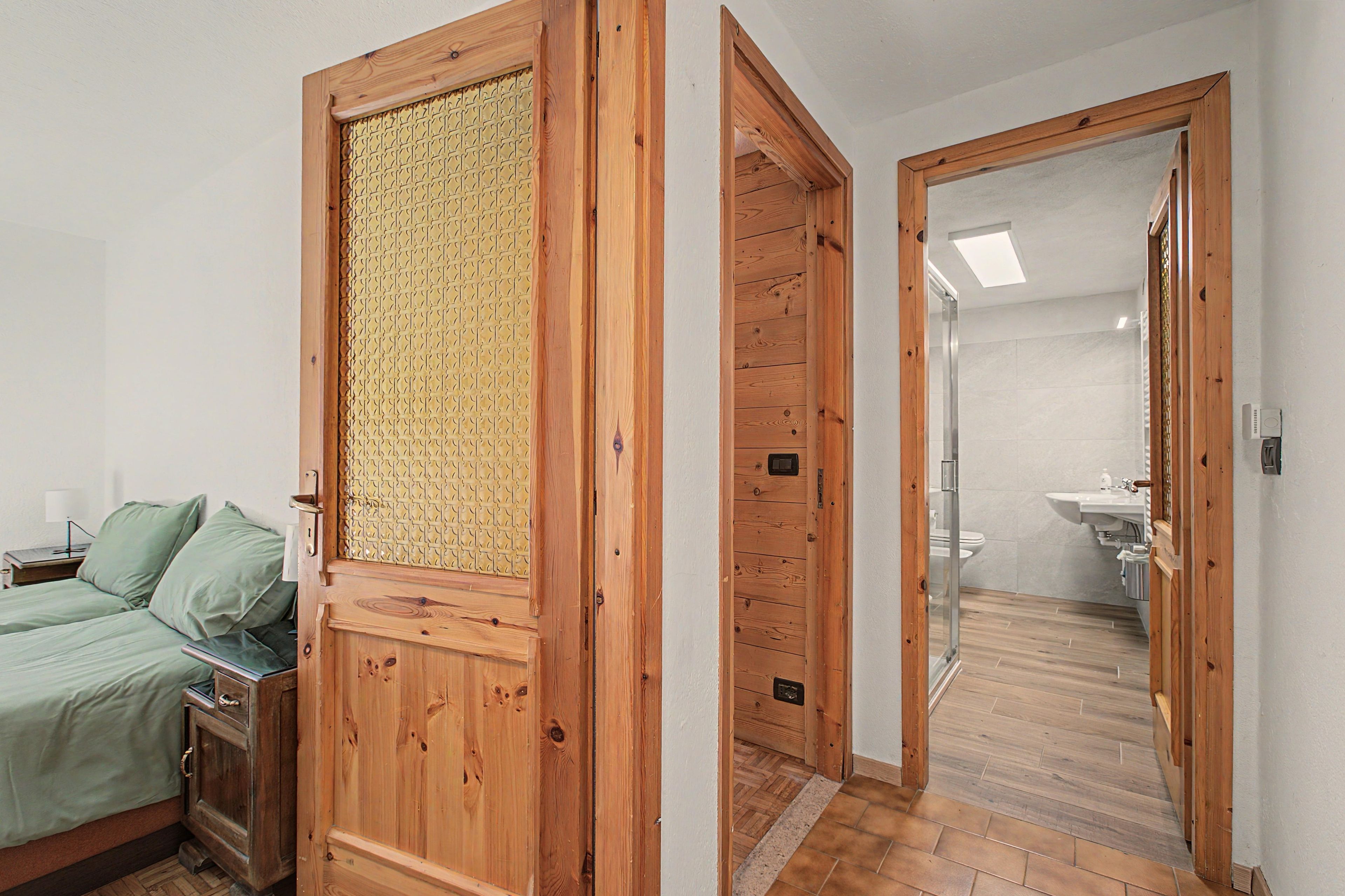 Een slaapkamer met een bed, een nachtkastje en een houten garderobe.