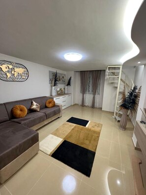 A modern living room with a sectional sofa, a world map wall art, a staircase, and a decorative plant. - The Guest from Naples (Napoli)