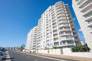 Ein mehrstöckiges Hotel mit Balkonen, blauem Himmel und einer Straße im Vordergrund.