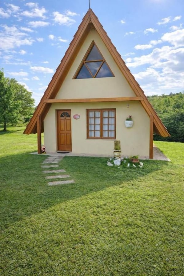 Una pequeña casa de un solo piso con techo triangular, puerta principal y ventana.