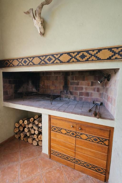 Una chimenea con un borde decorativo de azulejos, un mueble de madera debajo y una cabeza de animal montada encima.