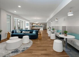 A modern living area with a sofa, ottomans, and a kitchen in the background.