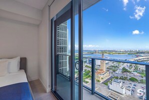 Spacious balcony view overlooking the waterfront, high-rise buildings, and highway alongside a corner of the bed. - Spacious Miami Condo - Near Brickell & Wynwood (Miami)